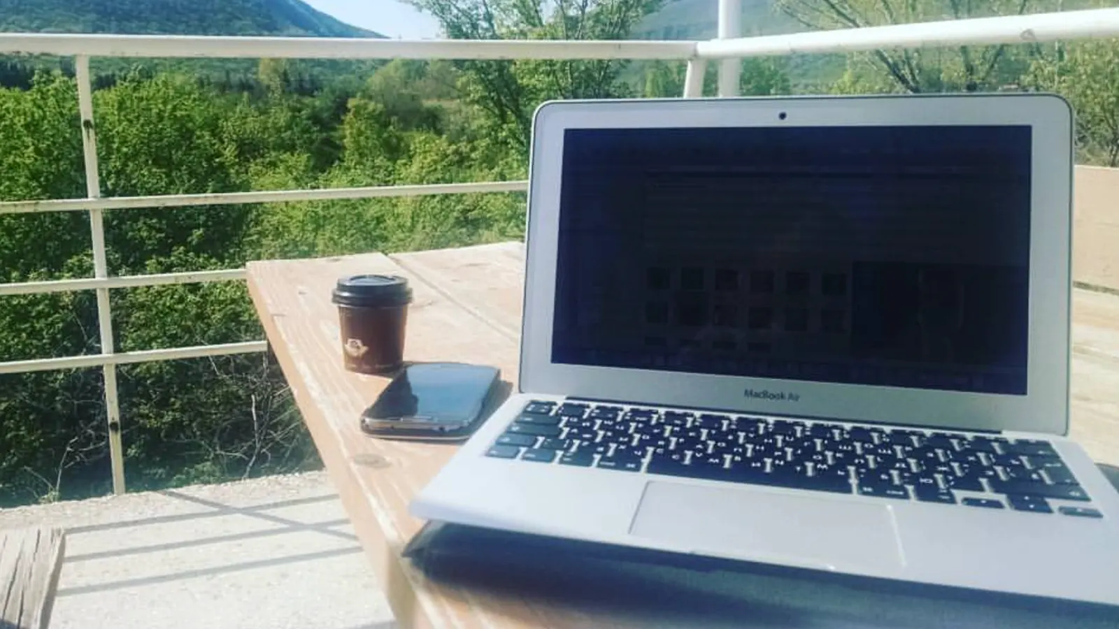 Робочий стіл радіолога: MacBook і кава на дерев’яному столі з видом на гори